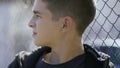 Teenager watching schoolmates playing on sportyard, disqualification spare bench