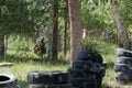 Landfill in the forest for a team game in paintball. A teenager wearing a black protective mask and camouflage clothes with arms i