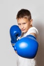 Teenager in a white T-shirt and boxing gloves on a gray background. Boxing lesson