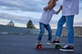 A teenager teaches a boy how to ride the skateboard.