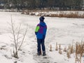 Teenager in winter goes to the ice of the lake. danger