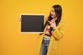 Teenager younf school girl holding school empty blackboard on yellow background. Portrait of a teen female