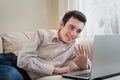 Young man lying on sofat and using laptop at home Royalty Free Stock Photo