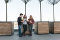 Teenagers eat street food, friends boy and two girls on city street with burgers and orange juice. City background, golden hour Royalty Free Stock Photo