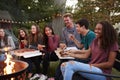 Teenagers at a fire pit eating take-away pizzas, close up