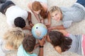 Teenagers on the floor examining a globe Royalty Free Stock Photo