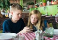 Teenagers having fun with mobile phones in cafe. Modern lifestyle and technology concept. Children sitting in restaurant and Royalty Free Stock Photo