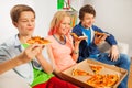 Teenagers holding pizza pieces and eating