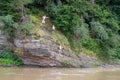 Teenagers jump from a cliff into a mountain river. Dangerous and extreme vacation on the beaches; Ukraine, Skole, July, 26, 2019.