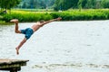 Teenagers jump into the water and swim in the lake on a hot summer day. Active recreation on an open pond. Children jump into the Royalty Free Stock Photo