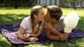 Teenagers kissing, lying on plaid in park, holding cotton candy, romantic date