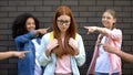 Teenagers pointing fingers teasing new smart classmate in eyeglasses school bag