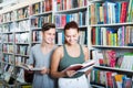 Teenagers reading book together while choosing literature Royalty Free Stock Photo