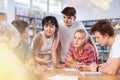 Teenagers in the school library are brainstorming together solving difficult problem