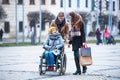 Teenagers and senior grandmother in wheelchair walking down the street in winter. Royalty Free Stock Photo