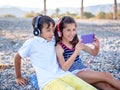 Teenagers sit on the beach with headphones look at the phone Royalty Free Stock Photo