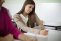Teenagers students sitting in the classroom and writing. Focus is on background Royalty Free Stock Photo
