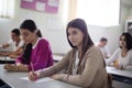 Teenagers students sitting in the classroom and writing. Girl looking at camera. Royalty Free Stock Photo