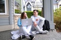 teenagers study online sitting on the street with a laptop Girl and boy drink coffee relax outdoor. Freelancer Royalty Free Stock Photo