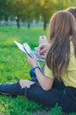 Teenagers studying together and lerning notes on the green lawn near college