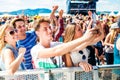 Teenagers at summer music festival in crowd taking selfie