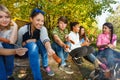 Teens grilling sausages sitting near yellow tent