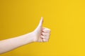 Teens hand with thumb up on yellow background. Symbol of perfect or accept