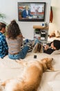 teens watching news and dog lying on bed