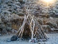 Teepee structure for shelter made of tree branches on a sandy beach in the Nevada desert. Royalty Free Stock Photo