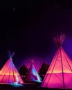 Teepees glowing colorfully at night under stars in Marfa, Texas