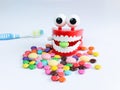 Teeth mock up with toothbrush and colorful candies.