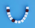 Teeth from sugar cubes on blue background, some brown sugar teeth, concept for sweet tooth, caries. Sugar is the cause of tooth