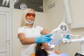 Teeth whitening by dental UV whitening device,dental assistant taking care of patient,eyes protected with glasses.Whitening treatm