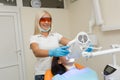 Teeth whitening by dental UV whitening device,dental assistant taking care of patient,eyes protected with glasses.Whitening treatm