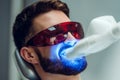 Teeth whitening. Man having teeth whitened by dental UV laser whitening device. Teeth whitening machine,eyes protected with