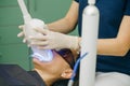Teeth whitening procedure. Dentist stomatologist whitening teeth for patient in medicine dental clinic with lamp