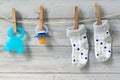 Teether, baby pacifier and socks hanging on clothesline on wooden background Royalty Free Stock Photo