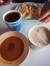Teh tarik with Roti Canai and black coffee in the background. A staple breakfast in Malaysia