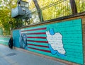 TEHERAN, IRAN - NOVEMBER 05, 2016: Iranian propaganda mural at the wall of former US embassy and veiled woman