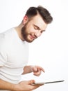 Tehnology, people and lifestyle concept: young bearded man wearing white t-shirt using a tablet computer Royalty Free Stock Photo