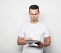 Tehnology, people and lifestyle concept: young man wearing white t-shirt using a tablet computer Royalty Free Stock Photo