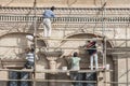 workers repairing ancient building in downtown beside urban street