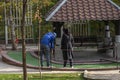 Young couple guy and girl playing mini golf in a city park