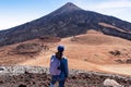 Teide - Hiking woman with backpack standing on the summit Pico Viejo with scenic view on the peak of volcano Pico del Teide