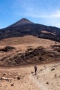 Teide - Woman with backpack on volcanic desert terrain hiking trail leading to summit volcano Pico Viejo, Tenerife, Spain.