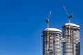 Two building crane attached to the construction of a modern high-rise building at the Royalty Free Stock Photo