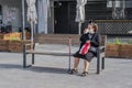 TEL-AVIV, ISRAEL - MARCH 29, 2020: A sweet granny sits on a bench on the street during a pandemic and drinks coffee. She is in a