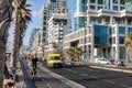 skyline and sand beaches of Tel Aviv city on sunset. A man rides a scooter along a bike path along