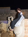 A girl - a member of the Knights of Jerusalem club, dressed in the traditional costume of a medieval lady, sits on a bull statue a Royalty Free Stock Photo