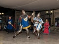 Members of the Knights of Jerusalem club dressed in the traditional armor of a knight, are fighting on swords at night in the old